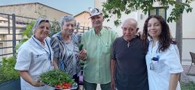 L'auxiliar d'infermeria Montserrat Batllori i la terapeuta ocupacional del Centre Maria Gay, Nerea Marín, al costat de persones residents aficionades a l'horticultura.